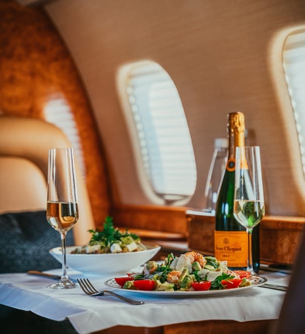Private-jet cabin table set with a plated salad and champagne
