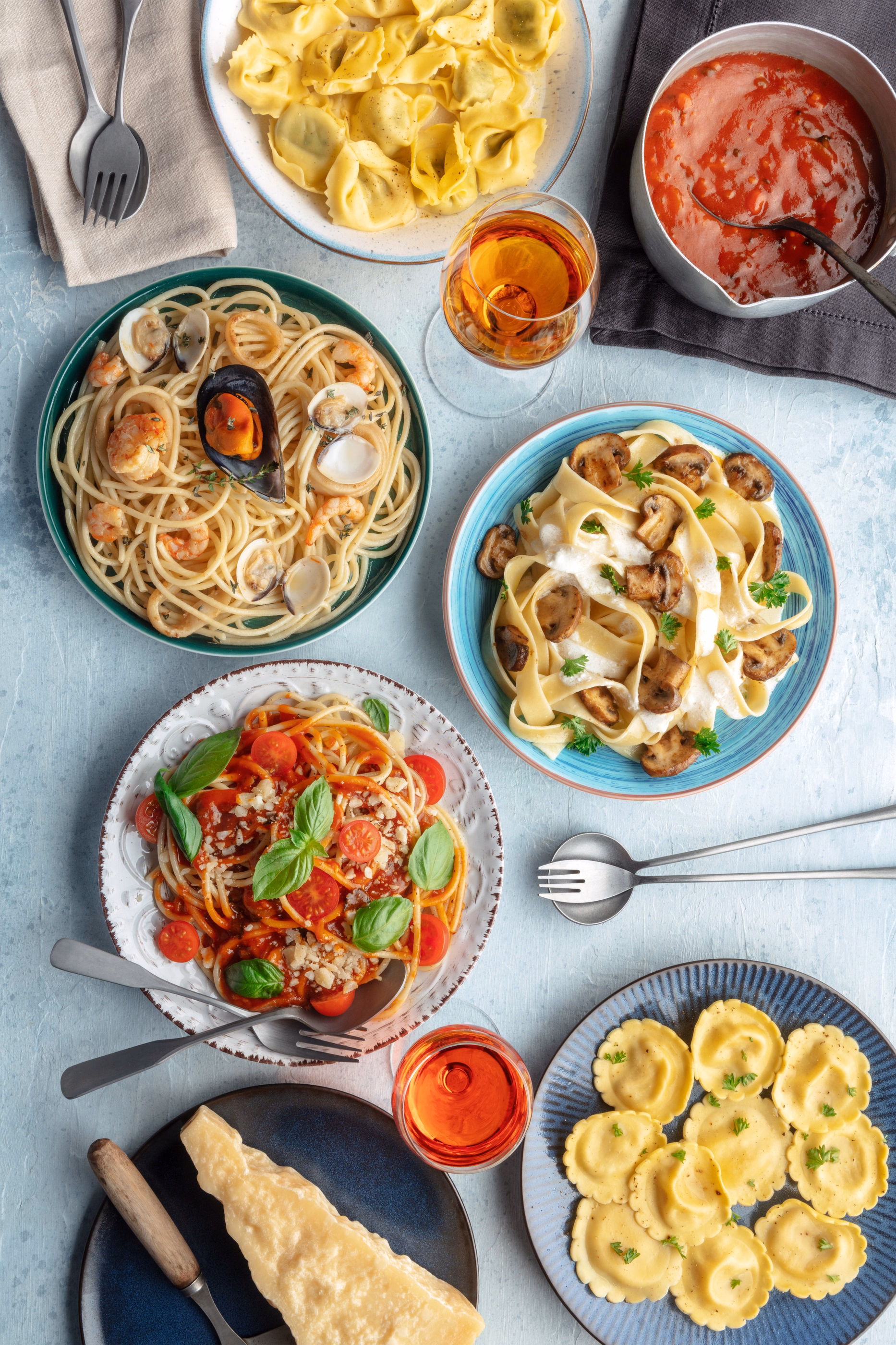Overhead spread of pasta, seafood, and wine.